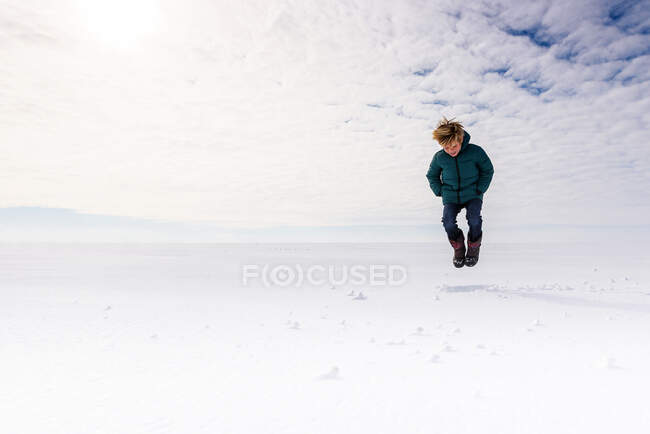 Junge springt mitten in der Luft in ein verschneites Feld, USA — Stockfoto