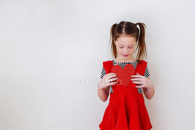 Retrato de uma menina segurando um coração na frente de seu peito — Fotografia de Stock