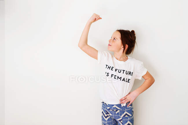 Chica de pie junto a una pared flexionando sus músculos - foto de stock