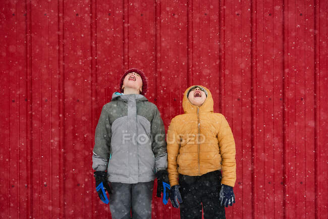 Двое детей ловят снежинки во рту, США — стоковое фото