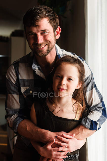 Retrato de un padre feliz abrazando a su hija - foto de stock