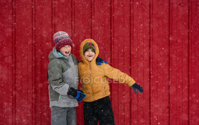 Two happy children messing about in front of a red house, USA — Stock Photo