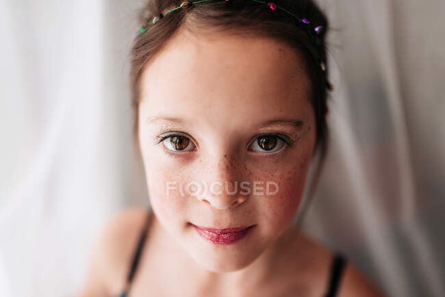 Portrait of a young girl wearing make-up standing by a curtain — Stock Photo