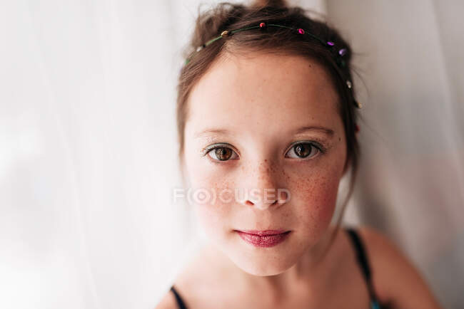 Retrato de uma menina vestindo maquiagem em pé por uma cortina — Fotografia de Stock