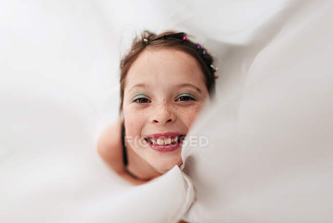 Portrait of a young girl wearing make-up wrapped in a curtain — Stock Photo