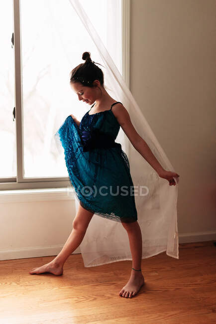 Ritratto di una giovane ragazza in piedi vicino ad una finestra che tiene la tenda — Foto stock