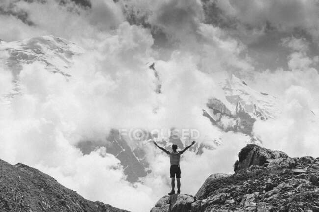Hombre de pie en la cima de la montaña con los brazos extendidos, Mont Blanc, Alta Saboya, Auvernia-Ródano-Alpes, Francia - foto de stock