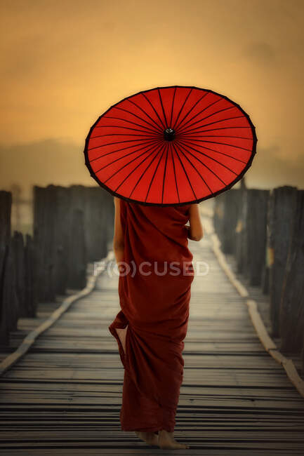 Rear view of novice monk walking across U Bein Bridge, Mandalay, Myanmar — Stock Photo