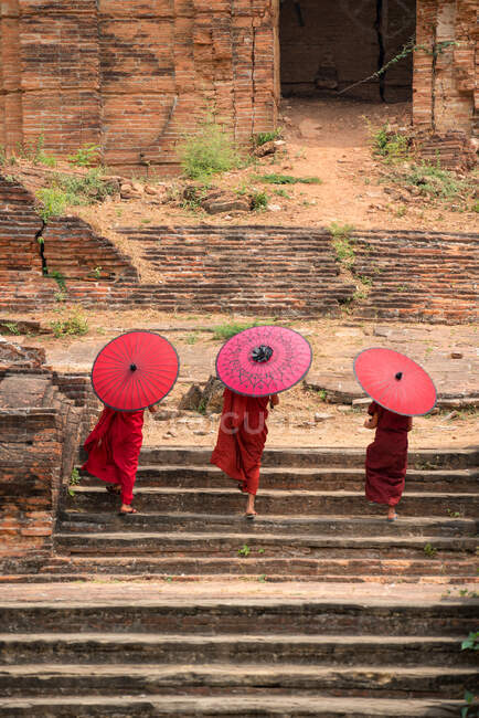 Tres monjes novicios subiendo escaleras a un antiguo templo, Bagan, Mandalay, Myanmar - foto de stock