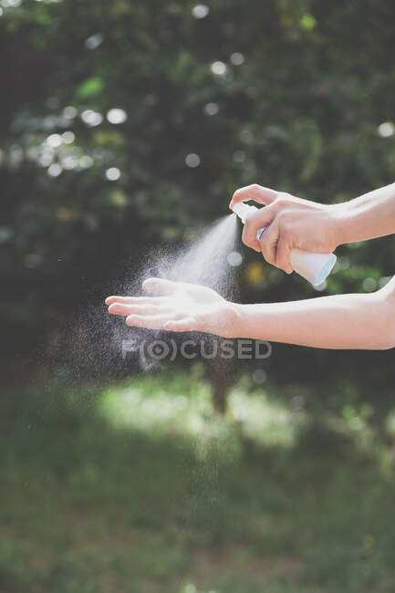 Menino pulverizando higienizador de mão em sua mão — Fotografia de Stock