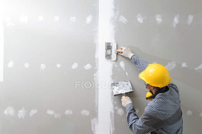 Rear view of a plasterer plastering walls — Stock Photo