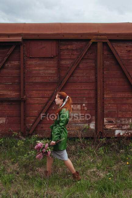 Жінка, що йде на відкритому повітрі з купою бузкових квітів — стокове фото
