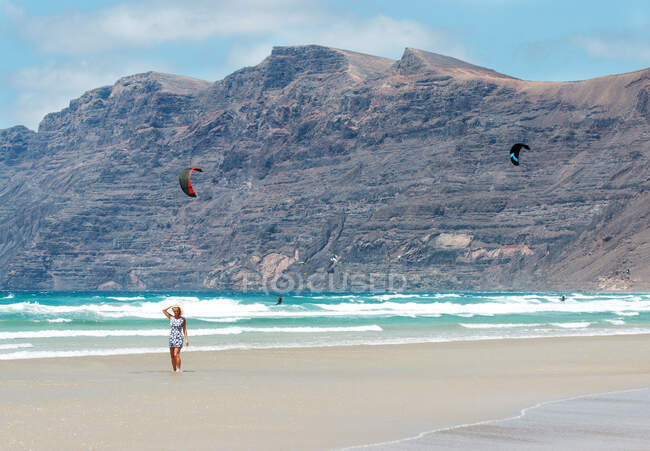 Hermosa mujer en un vestido de verano en la playa de Famara, Lanzarote, Islas Canarias, España - foto de stock