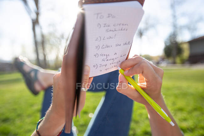 Donna sdraiata in un parco a scrivere una lista di cose da fare, Stati Uniti — Foto stock