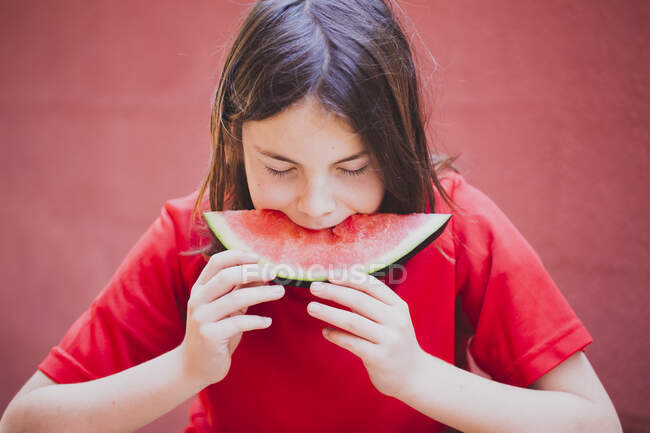 Boy with long hair eating a slice of watermelon — Stock Photo