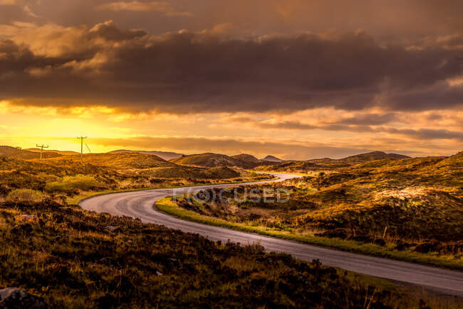 Empty Road a través del paisaje rural en Sunset, Escocia, Reino Unido - foto de stock