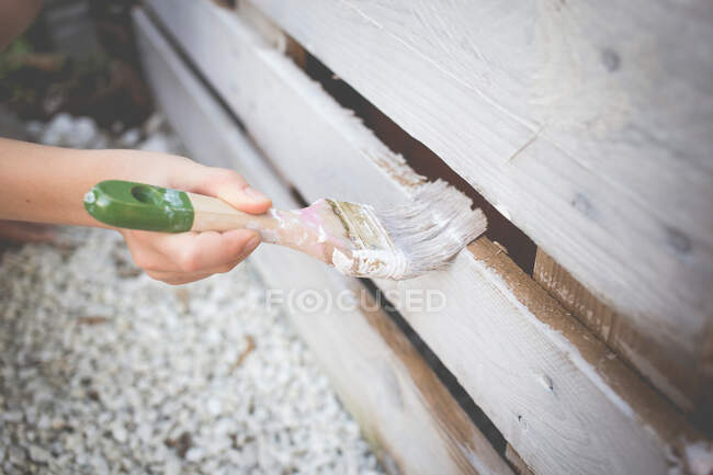 Painting a recycled pallet with a white brush — Stock Photo