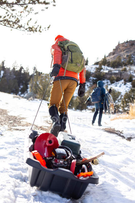 Uomo che tira slitta con attrezzatura da pesca sul ghiaccio, Wyoming, USA — Foto stock