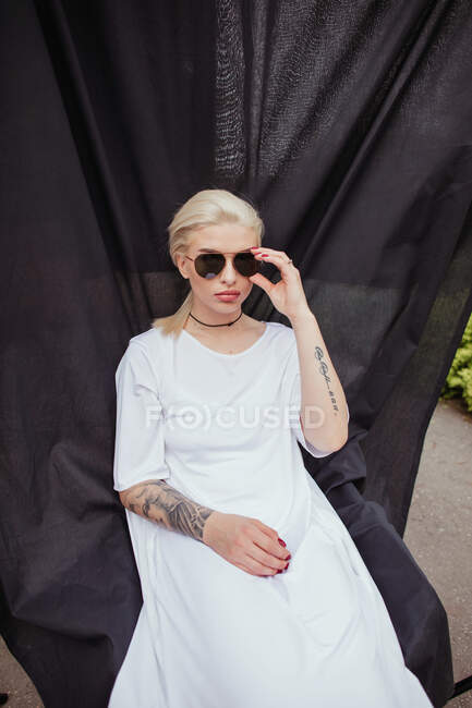 Retrato de uma mulher sentada em uma cadeira coberta de tecido — Fotografia de Stock