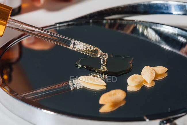 Pipette with argan oil and argan seeds — Stock Photo