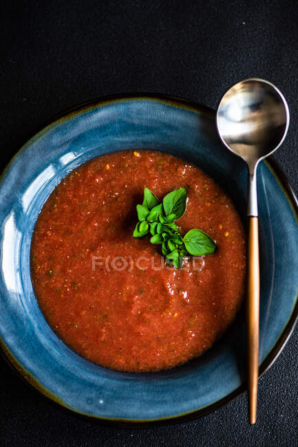 Soupe à la crème de tomate à l'origan servie dans un bol et couverts sur fond de béton avec espace de copie — Photo de stock