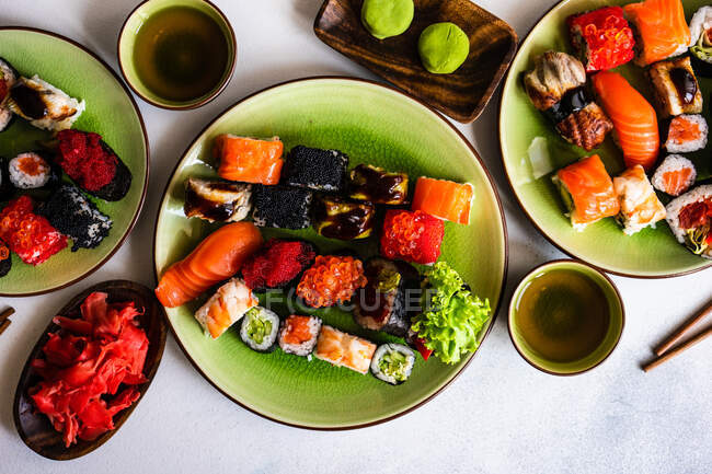Overhead view of a nigiri and maki roll sushi selection with wasabi, pickled ginger and green tea — Stock Photo