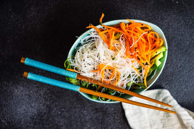 Vista aérea de fideos asiáticos y ensalada de verduras con palillos - foto de stock