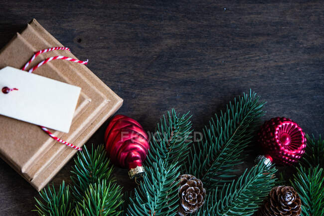 Montón de regalos de Navidad junto a piñas, ramas de abeto y adornos de Navidad en una mesa de madera - foto de stock