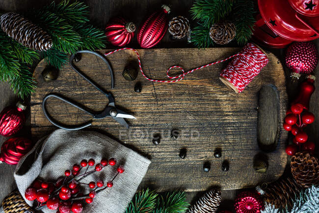 Enfeites de Natal, pinecone, ramos de abeto, bagas, cordas e tesouras em uma tábua de cortar — Fotografia de Stock