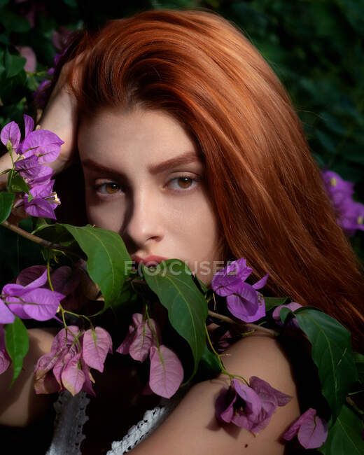 Porträt einer schönen rothaarigen Frau inmitten von Bougainvillea-Blumen, Italien — Stockfoto