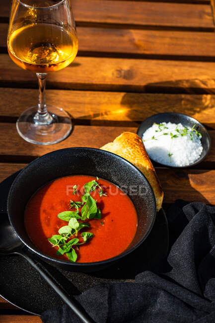 Ciotola di zuppa di gazpacho con pane francese e un bicchiere di vino rosato — Foto stock