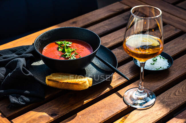 Sopa de gazpacho con una rebanada de pan tostado y una copa de vino rosa - foto de stock