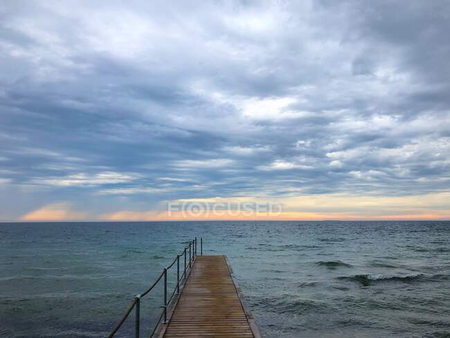 Wooden jetty at sunrise with rain storm approaching, Nordby, Samsoe, Denmark — Stock Photo
