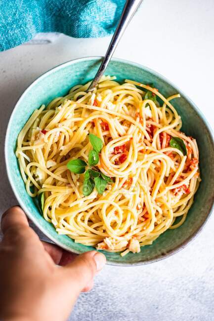 Рука тягнеться до миски Спагетті з томатним соусом і сиром — стокове фото