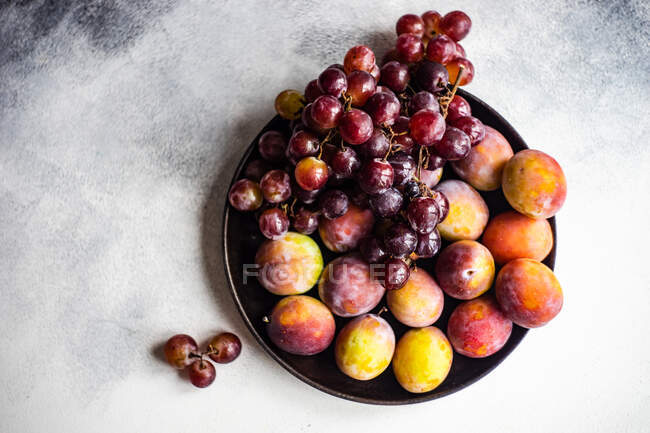 Plate of plums and grapes — Stock Photo