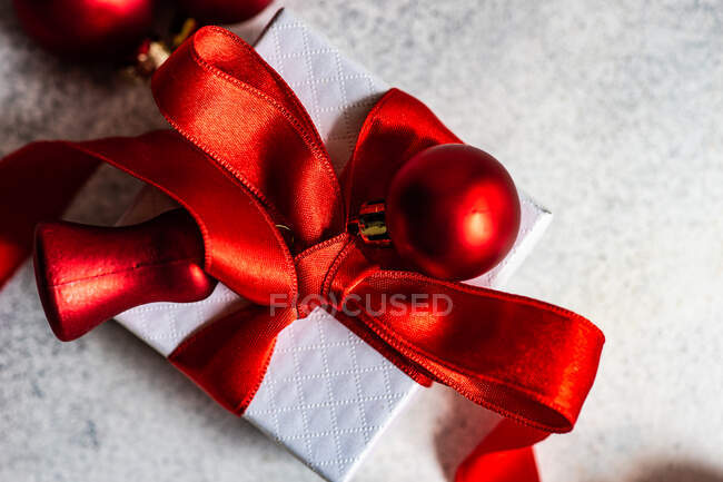 Caja de regalo envuelta atada con una cinta roja y adornos de Navidad — Stock Photo