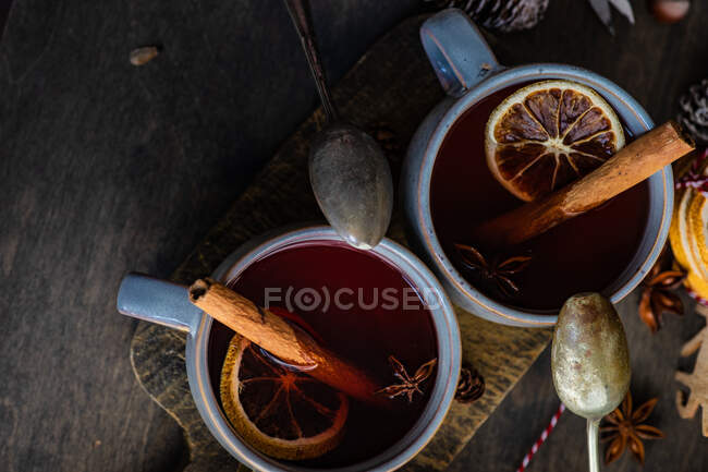 Copas de vino caliente con canela y naranja en una tabla de cortar - foto de stock