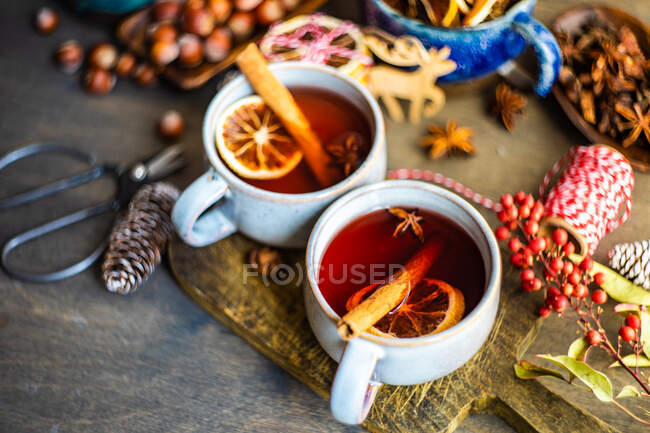 Tasses de vin chaud avec cannelle et orange sur une planche à découper — Photo de stock