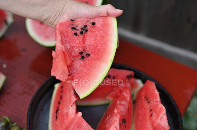 Hand greift nach einem Stück geschnittener Wassermelone — Stockfoto