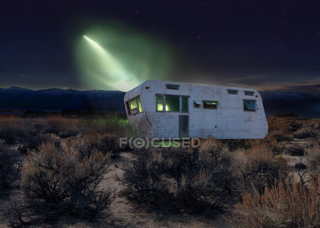 Mysterious light shining on an old abandoned caravan in the desert, USA — Stock Photo
