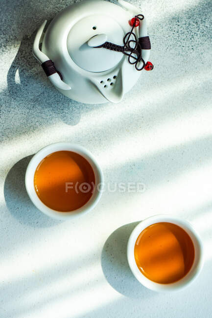 Dos tazas de té y una tetera sobre una mesa - foto de stock