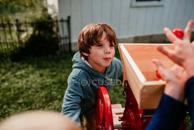 Хлопець, який допомагає натискати яблука, щоб зробити сидр, США — стокове фото