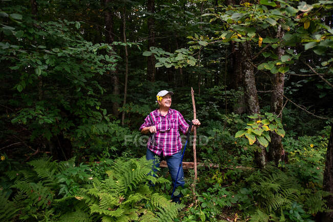 Retrato de una mujer mayor sonriente caminando por el bosque, EE.UU. - foto de stock