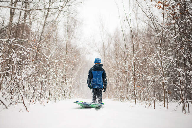 Ragazzo che tira una slitta attraverso la neve, Wisconsin, USA — Foto stock