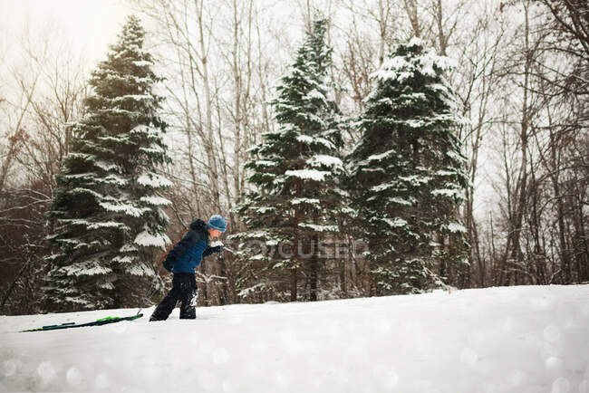 Boy pulling a sledge up a hill in the snow, Wisconsin, USA — Stock Photo