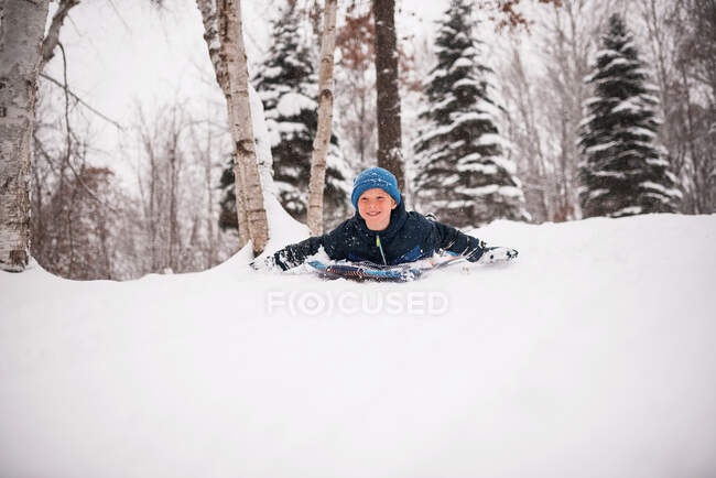 Lächelnder Junge beim Rodeln im Schnee, Wisconsin, USA — Stockfoto