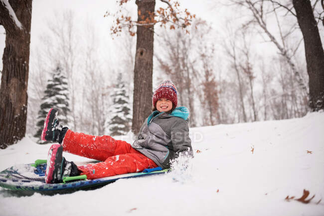 Chica feliz trineo en la nieve, Wisconsin, EE.UU. - foto de stock