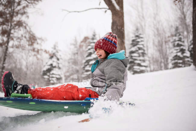 Chica feliz trineo en la nieve, Wisconsin, EE.UU. - foto de stock
