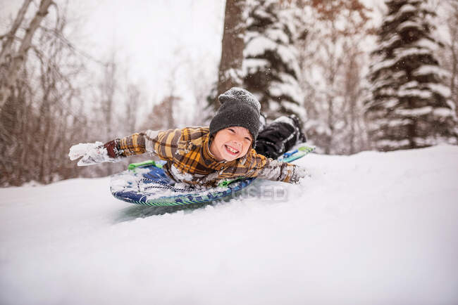 Ragazzo sorridente slittino nella neve, Wisconsin, Stati Uniti d'America — Foto stock