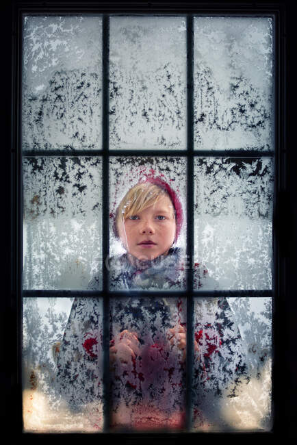 Ragazzo che guarda attraverso una finestra gelida, USA — Foto stock